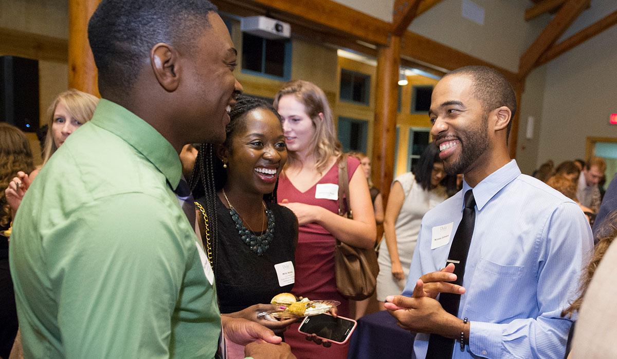 Group of students laughing and talking at homecoming reception