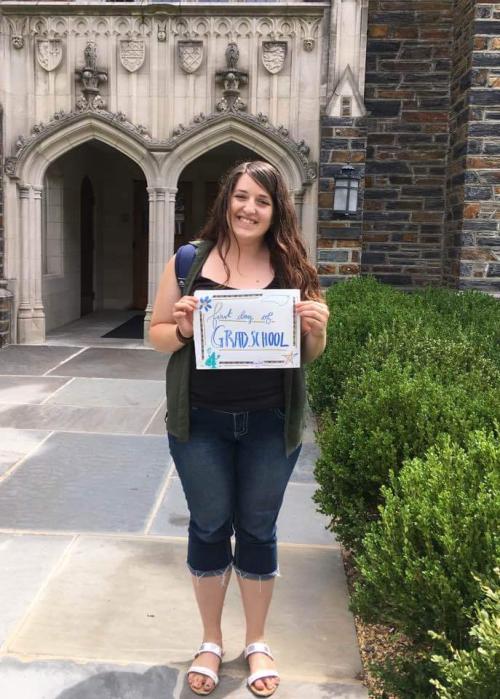 Photo of Jessica Covil-Manset with a sign that reads "First day of Graduate School"