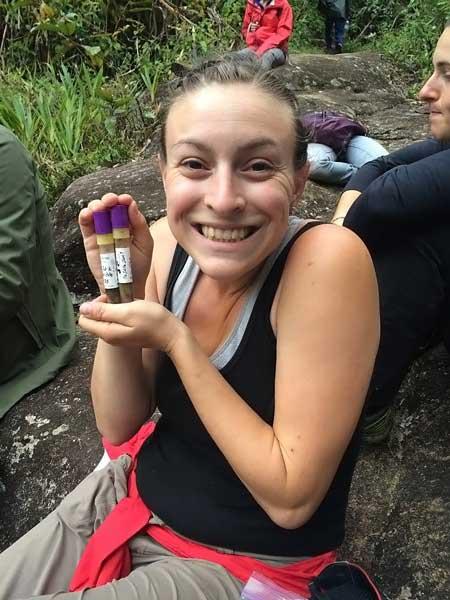 Lydia Greene holding up test tubes of lemur droppings.