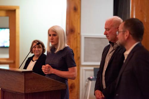 Angela Eberts speaks at a podium with three people at her side